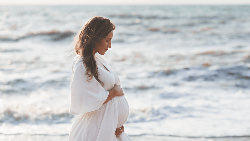 Pregnant woman on a beach during summer time.