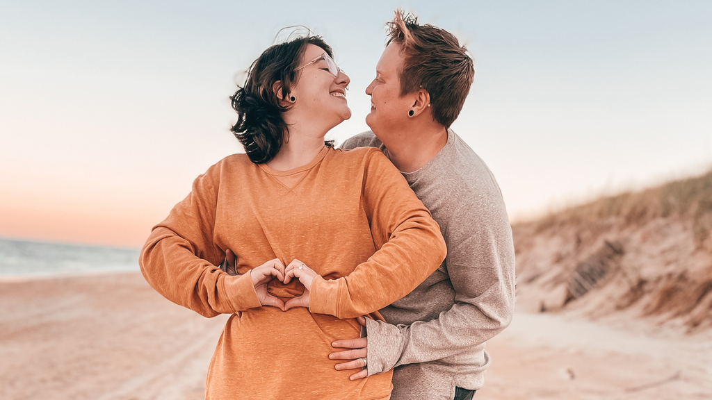 LGBTQ+ couple, Cindy and Sarah embracing on a beach