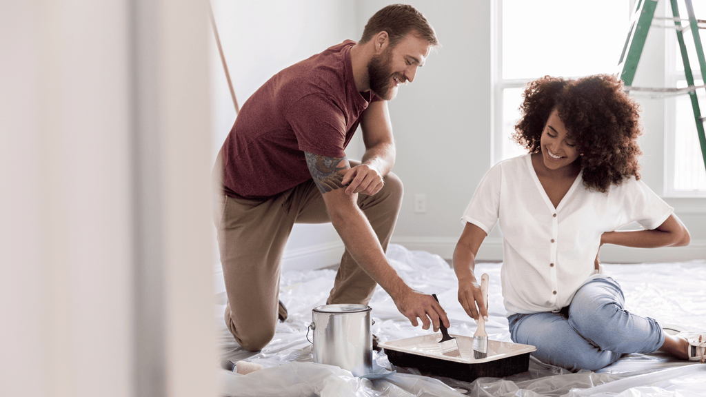 Happy man and pregnant woman painting a nursery room