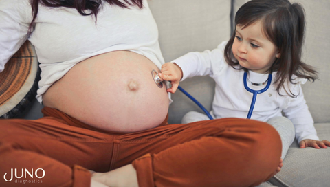 A little girl checking on her mom's pregnant belly 